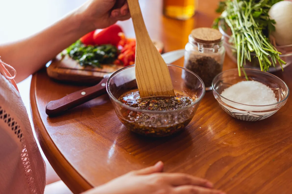Bol avec ingrédients de marinade : huile, acide, herbes et épices mélangés