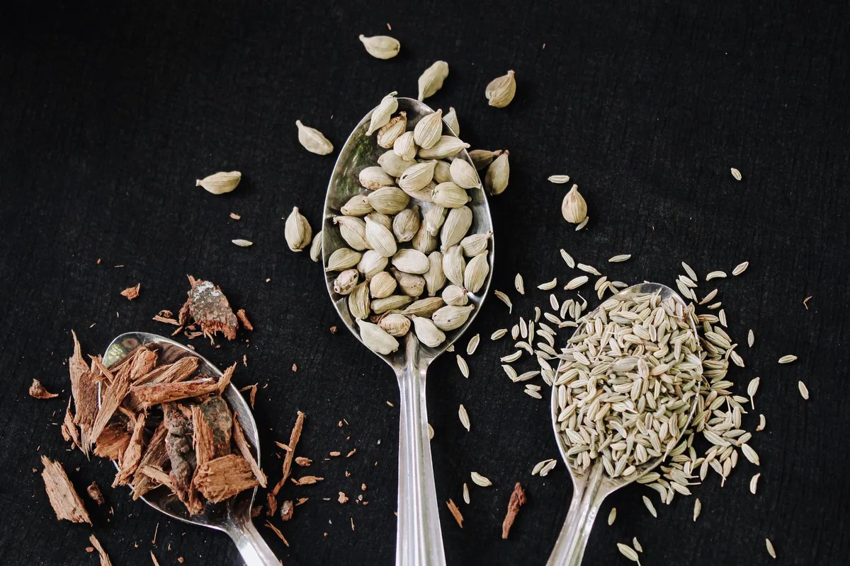 Épices entières : graines de cumin, bâtons de cannelle et gousses de cardamome