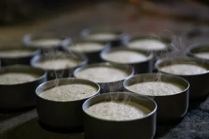 Mains versant des épices dans un plat de couscous fumant avec légumes et viande