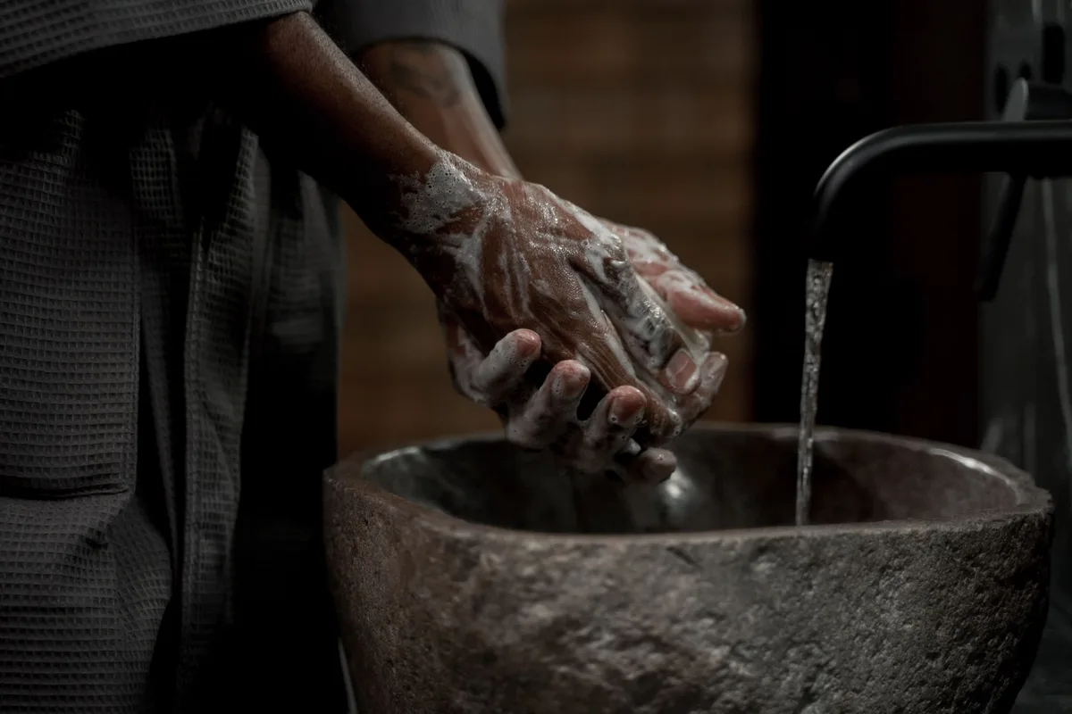 Mains sous l'eau chaude avec mousse de savon lors d'une douche