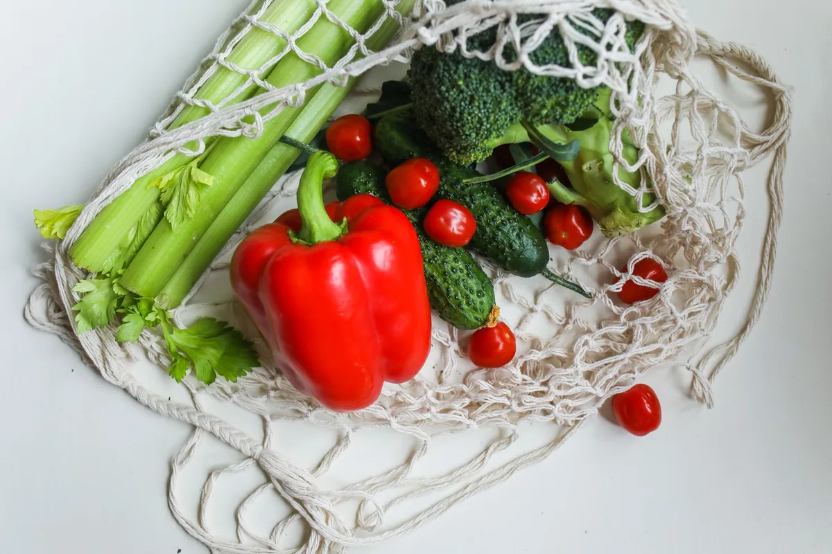 Mains arrangeant des légumes frais, fruits et protéines maigres sur une table en lumière naturelle