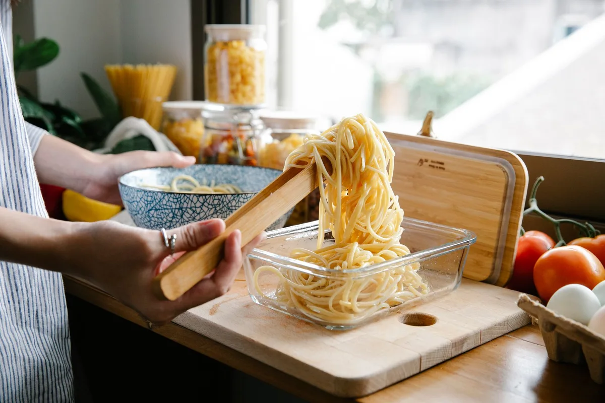 Mains examinant une boîte de pâtes sèches et son étiquette dans une cuisine