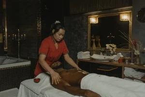 Mains massant doucement l'abdomen d'une personne, verre d'eau à proximité, lumière naturelle douce.