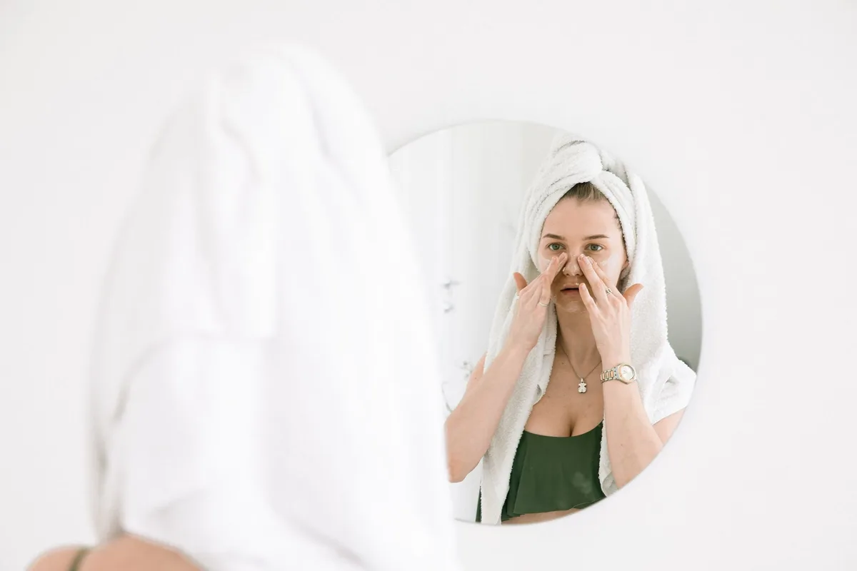 Application d'eau de rose comme tonique sur le visage avec un coton