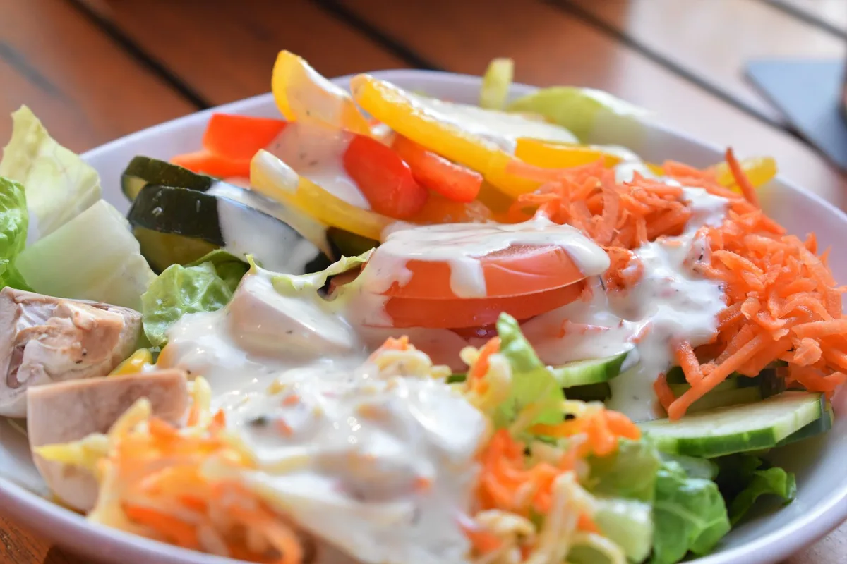 Mains préparant une salade colorée avec des légumes frais et des grains complets dans une cuisine lumineuse