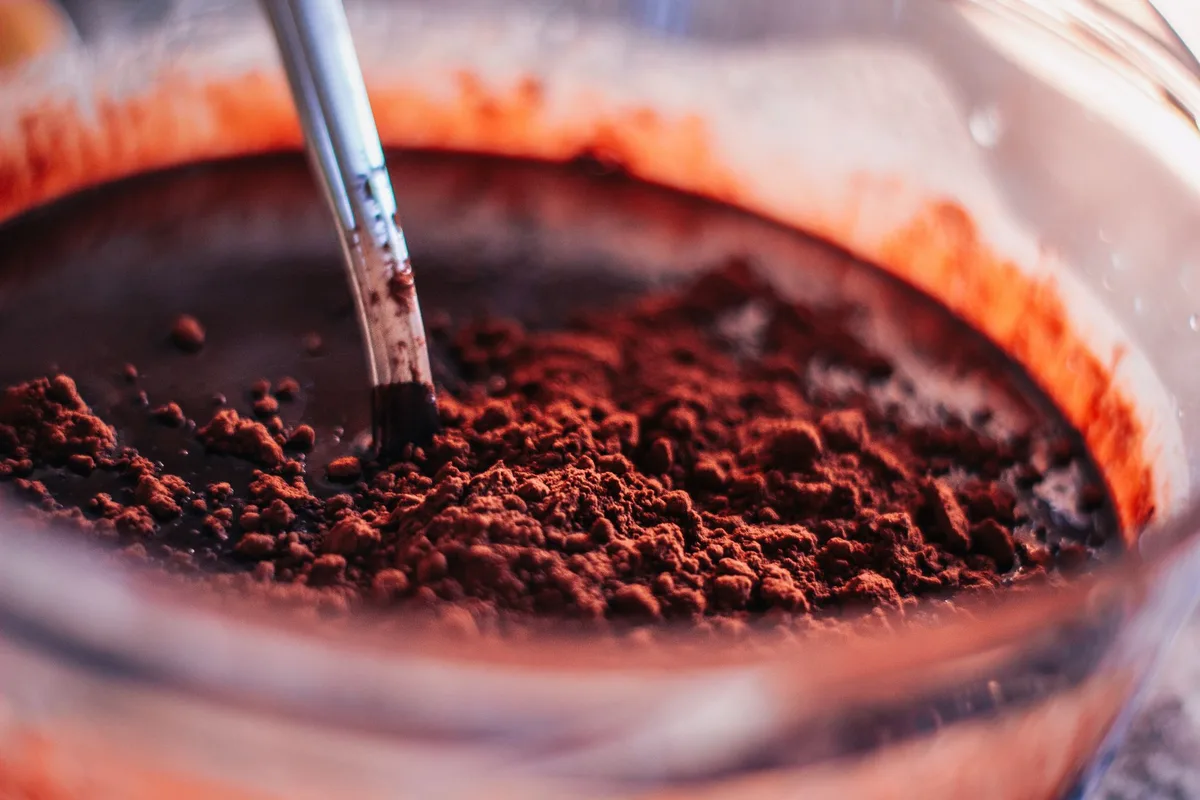 Préparation de la pâte de henné : poudre fine mélangée avec un liquide tiède dans un bol
