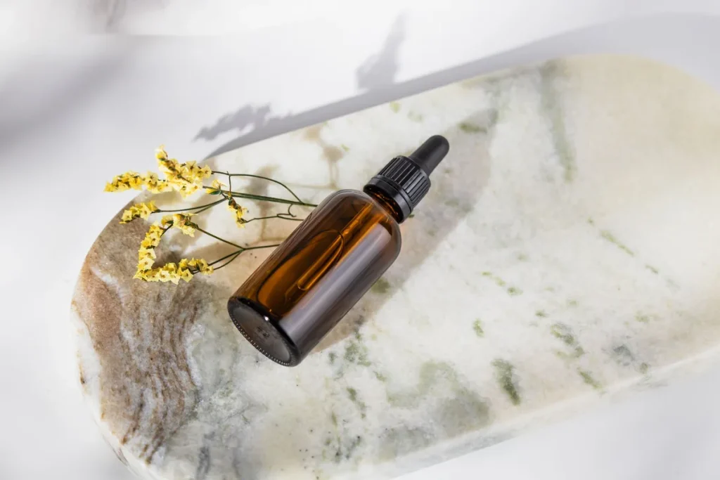Flacon d'huile de nigelle ambrée avec graines de cumin noir fraîches sur une surface neutre
