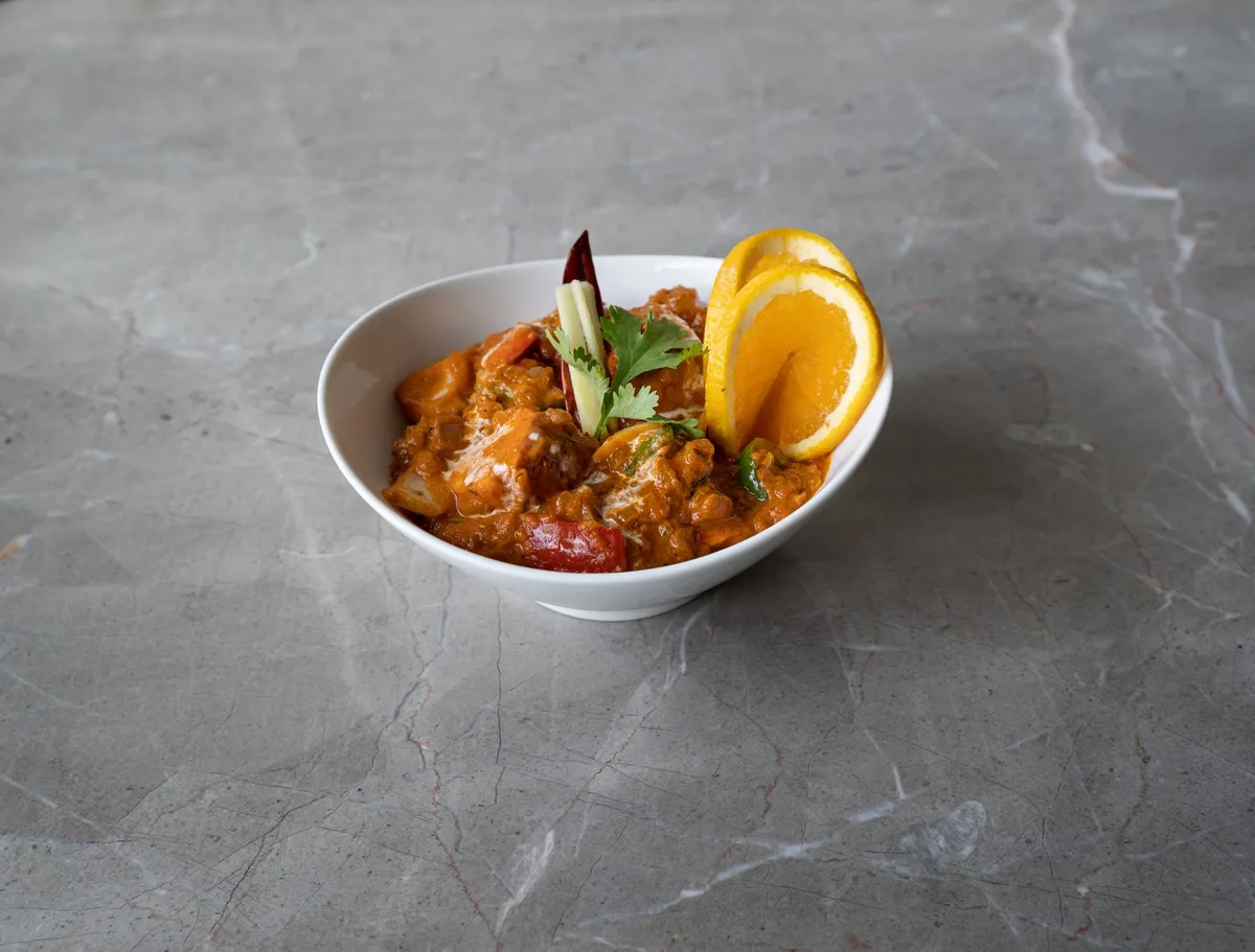Bol fumant de curry de pois chiches dorés avec épices aromatiques en arrière-plan