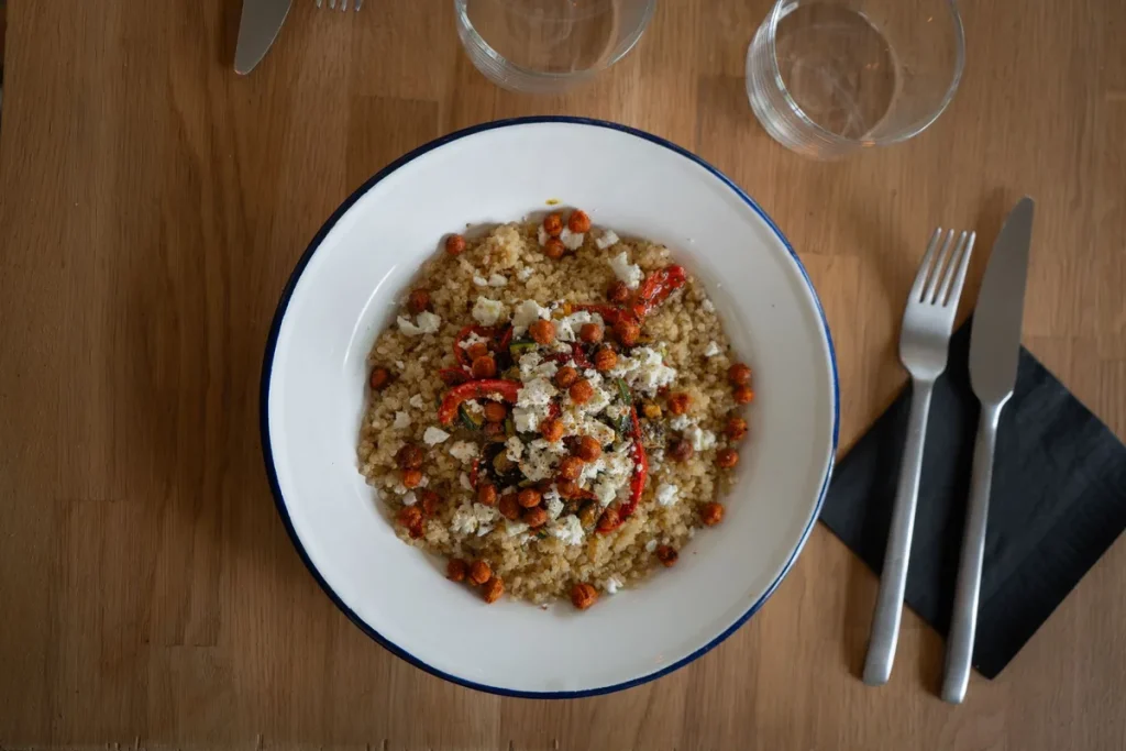 Tajine en terre cuite et couscous à la vapeur côte à côte sur une table de cuisine