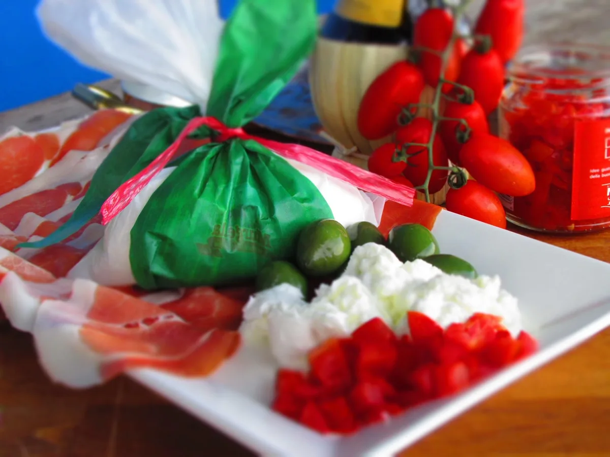 Burrata rose ouverte sur une assiette, garnie de fraises fraîches et d'herbes