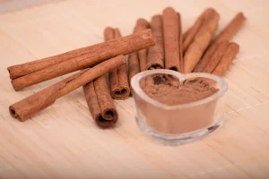 Bâtons de cannelle et poudre de cannelle dans des bols en céramique sur un plan de travail en bois