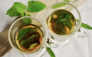 Tasse de thé ayurvédique entourée de plantes médicinales, pierres et bougies sur une table en bois