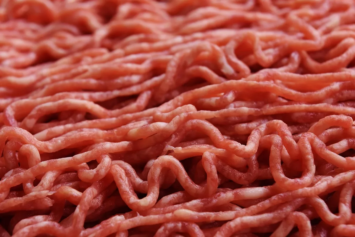 Haché de bœuf dans un bol avec oignon râpé et épices, prêt à être mêlé