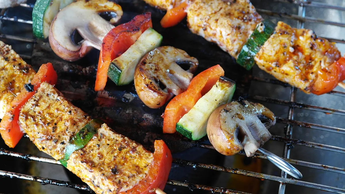 Mains en train d'enrouler de la farce autour d'une brochette métallique pour kefta