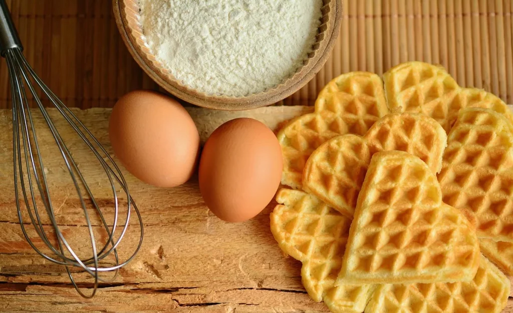 Mains triant poivre, bâtons de cannelle et cardamome sur une table en bois baignée de jour