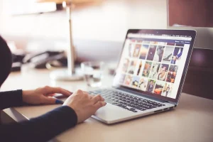 Personne rédigeant un email professionnel sur un ordinateur portable avec bloc-notes et stylo