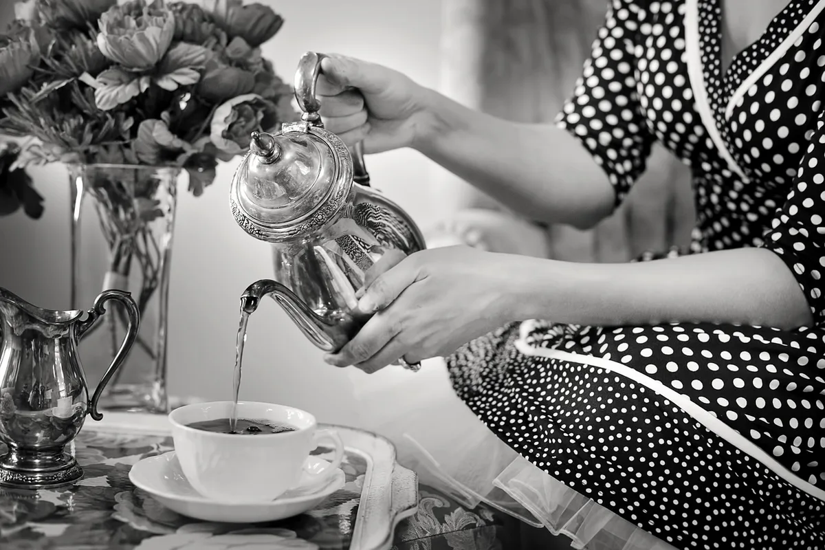 Infusion d'hibiscus versée d'une théière dans une tasse, lumière du jour