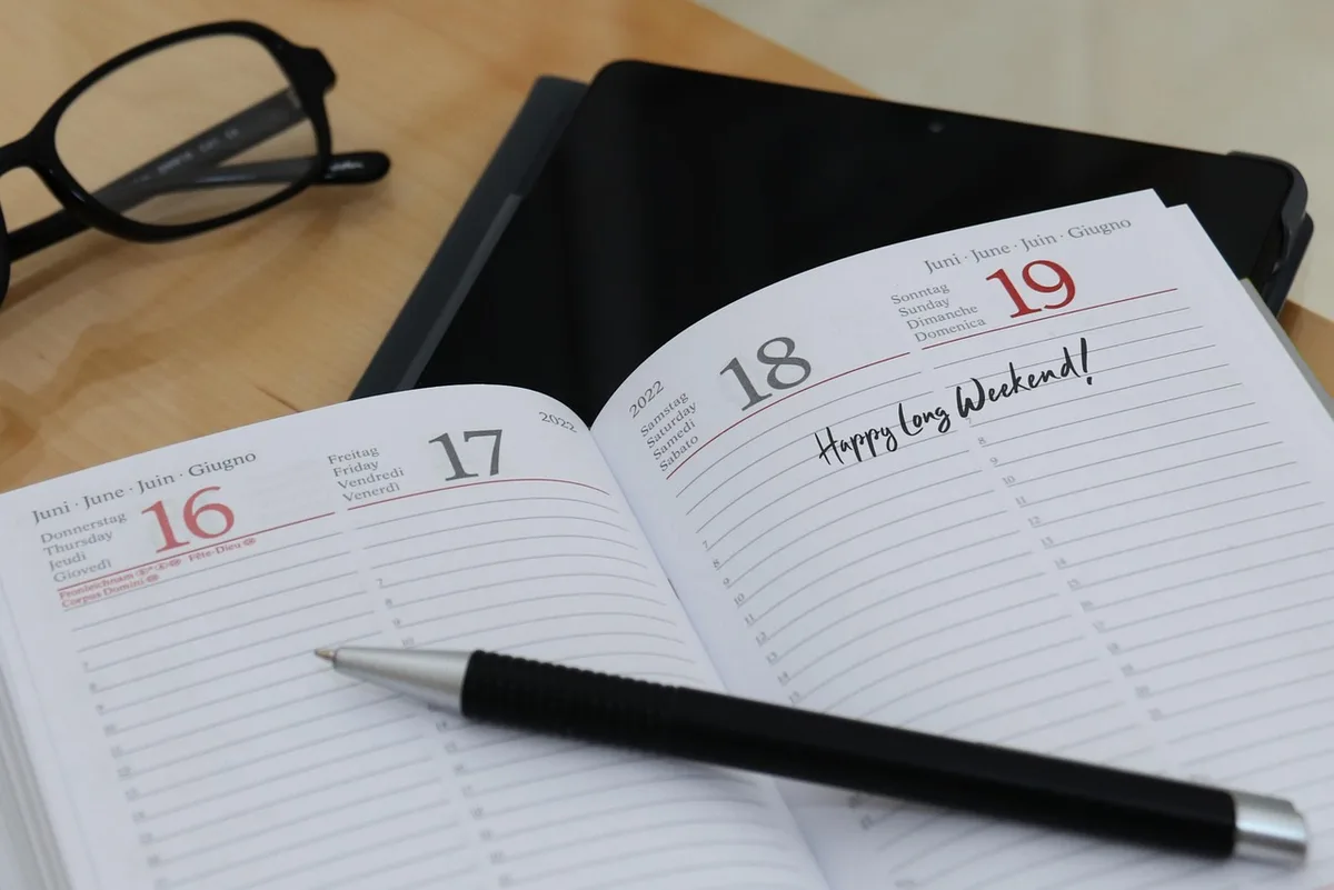 Bureau organisé avec un agenda ouvert et un ordinateur montrant une planification