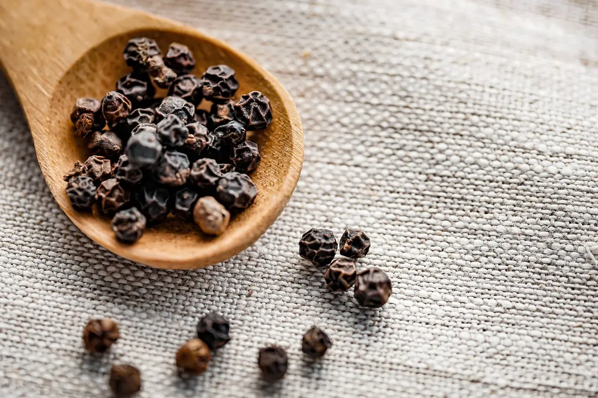 Gros plan sur grains de poivre entiers dans un bol, fermes et aromatiques