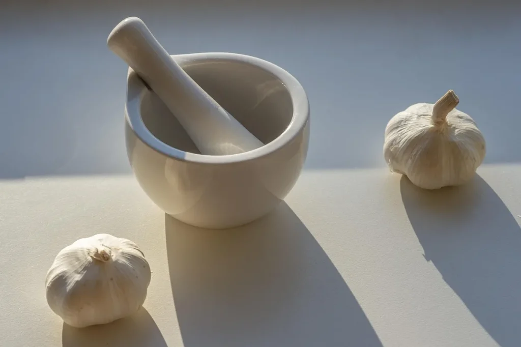 Jars de poivres entiers, mortier en bois et main saupoudrant du poivre fraîchement concassé