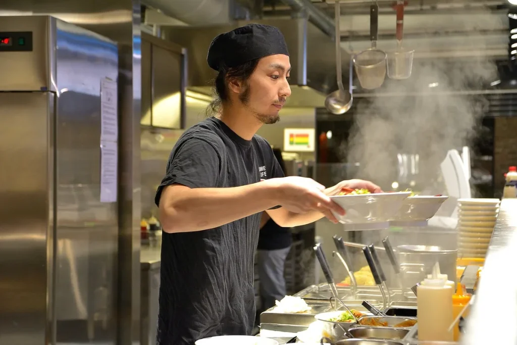Bol en bois de guacamole maison sur un plan de travail ensoleillé avec avocat et citron vert