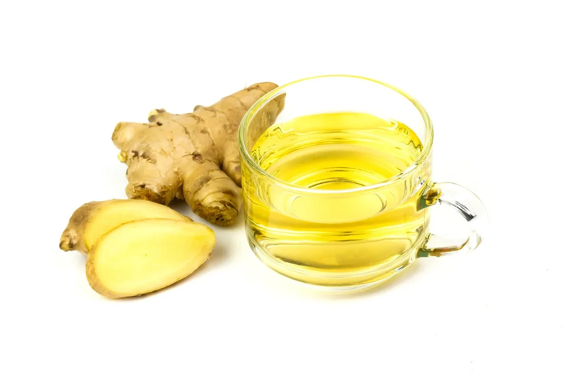 Tasse de tisane posée près d'une main qui touche la gorge, évoquant apaisement