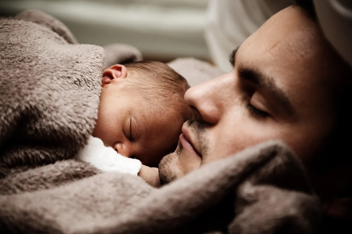 Parents tenant un flacon d'huile essentielle près d'un diffuseur, en plein jour