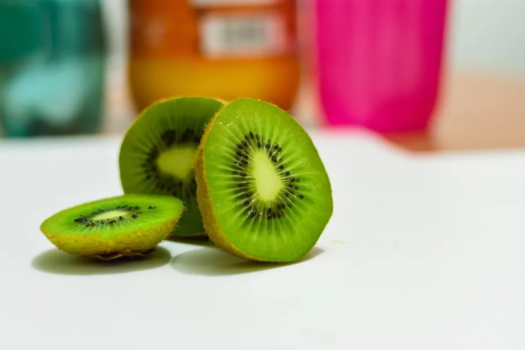 Bol de fruits colorés (agrumes, kiwis) sur une table de cuisine baignée de lumière du jour