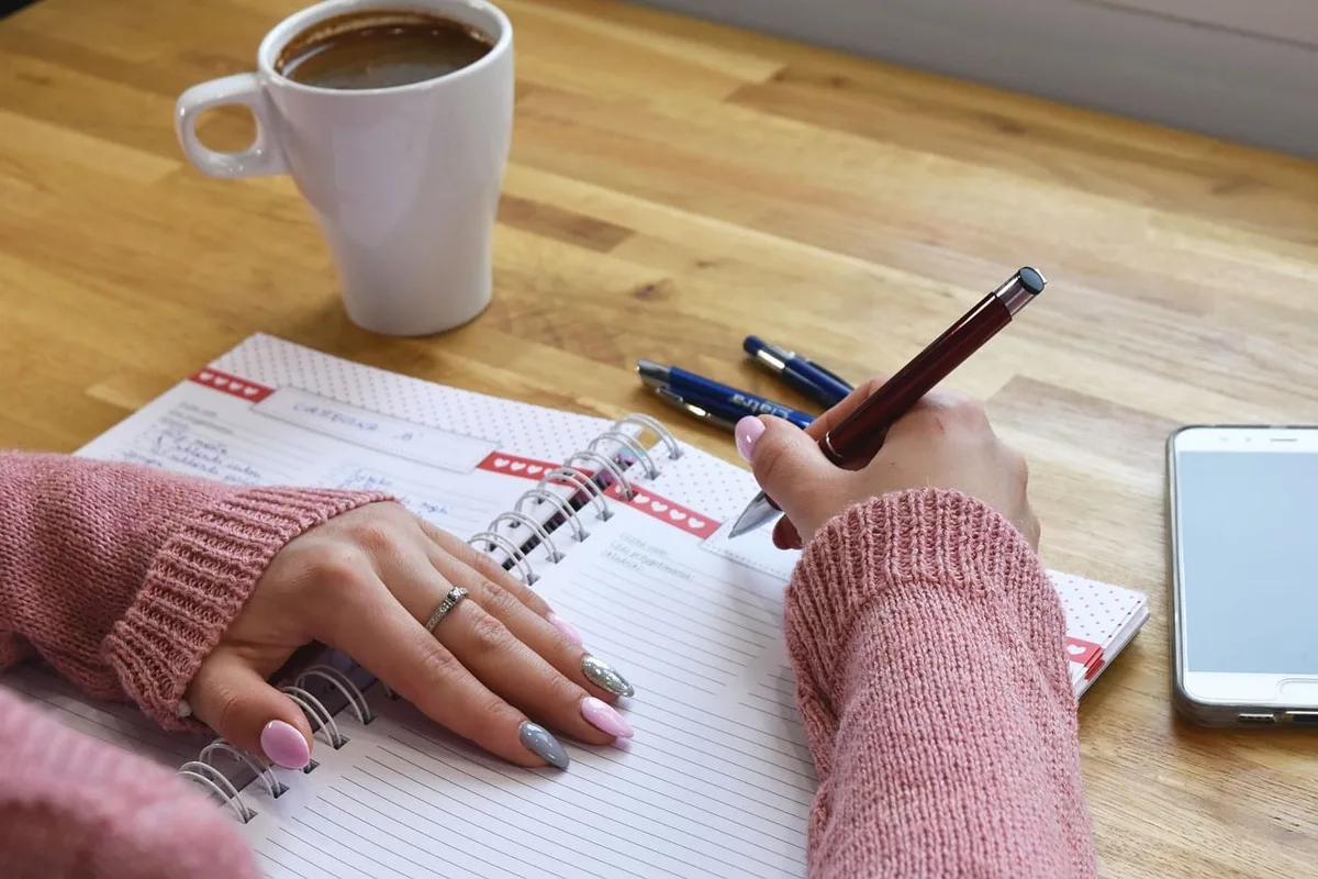 Carnet de planification ouvert avec liste de tâches sur une table ensoleillée