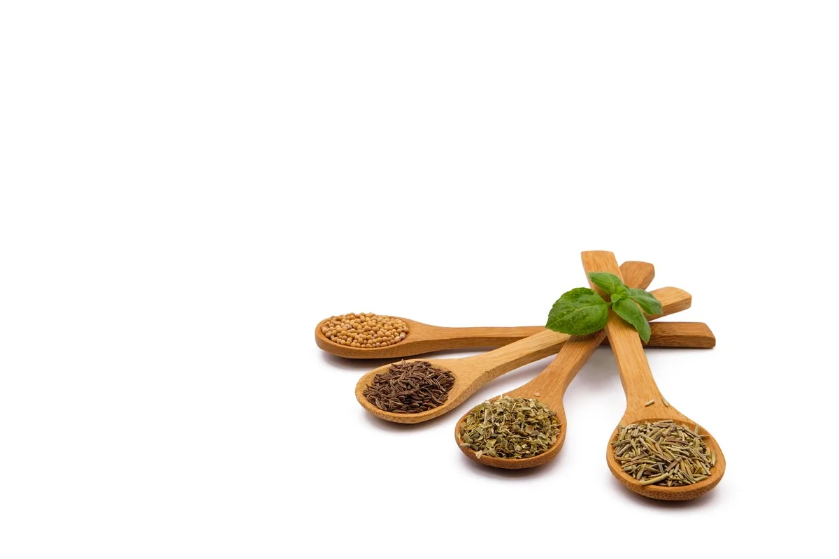 Cinq petites cuillères contenant fenugrec, fenouil, cumin, moutarde et nigelle