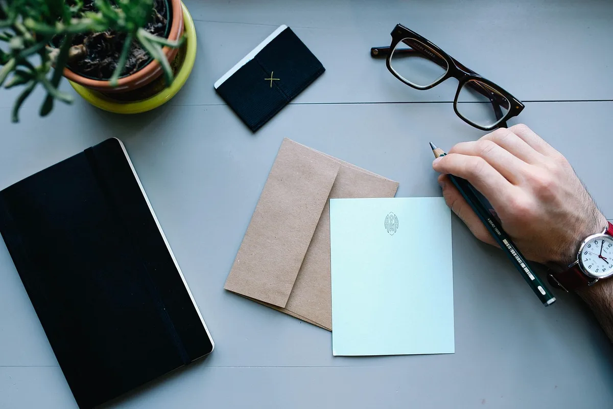 Main écrivant trois priorités dans un carnet au petit-déjeuner