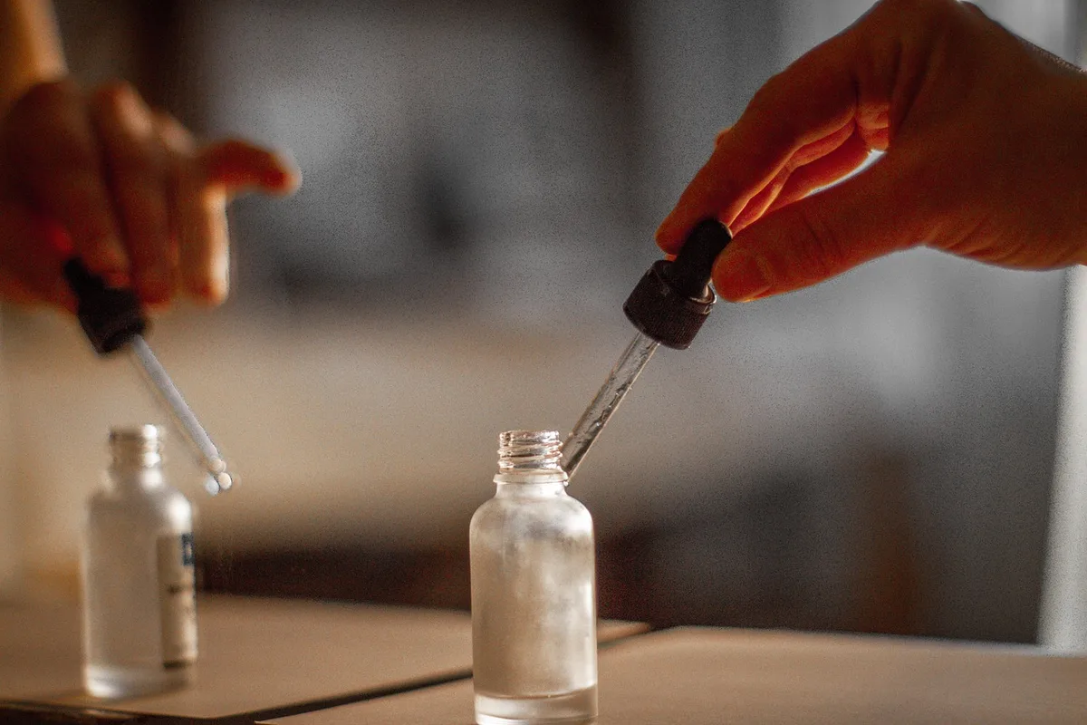 Mains préparant une dilution d’huile essentielle dans une huile végétale
